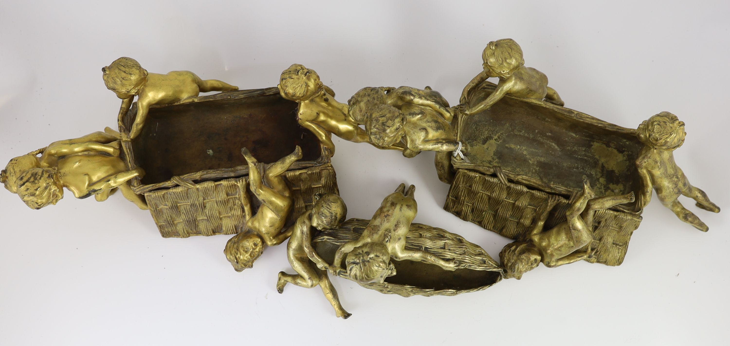 Raoul Francois Larche (French, 1860 - 1912). A set of three ormolu groups of children pushing and pulling large wicker baskets, largest length 45cm height 17cn smaller length 27cm height 16cm